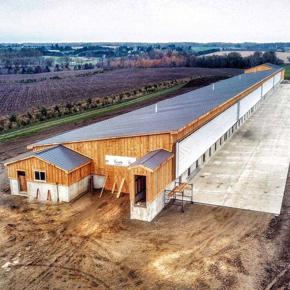 Aerial view of humane pig barn.  Monoslope roof with barn boards.  Outdoor area for the pigs. 