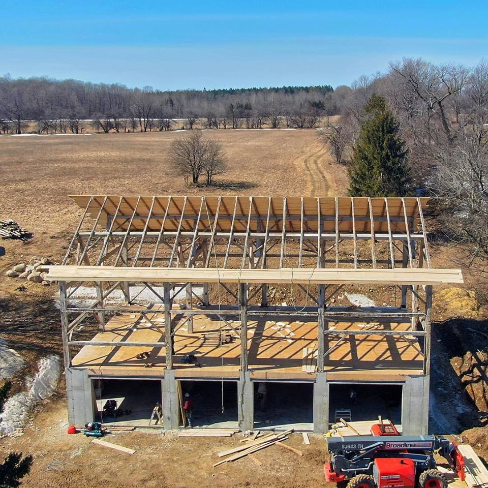 Timber frame barn relocation.  Reclaimed timber frame is installed on a new foundation.  Aerial view from a drone.