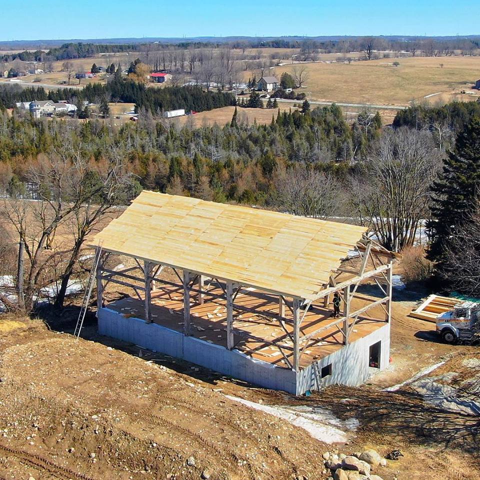 Timber frame barn relocation.  Reclaimed timber frame is installed on a new foundation.  Aerial view from a drone.