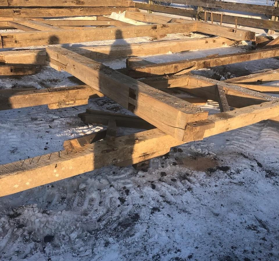 Timer frame barn being relocated.  Timber frames have been placed on the snow covered ground